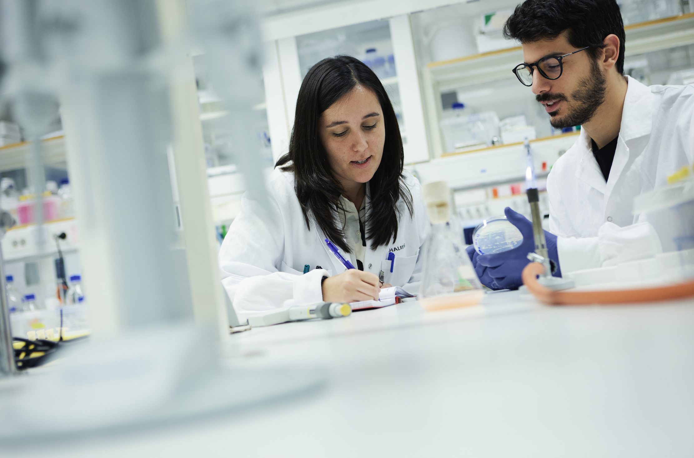 Porträtt av kvinna och man arbetandes i vitt labb